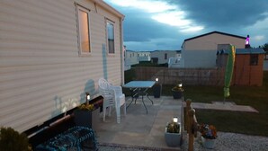 A residential area with a mobile home, outdoor furniture, and potted plants. - Taid's Retreat Silversands Cove Beach Lossiemouth (Lossiemouth)