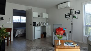 A modern, compact living space with a kitchenette, a dining area, and a bedroom.
