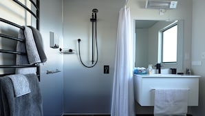 A modern bathroom with a shower, a white sink, and a mirror.