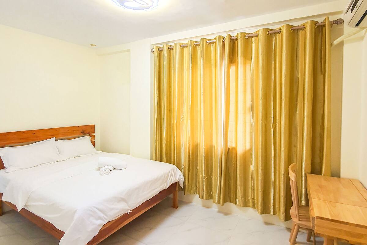 Una habitación de hotel con una cama, una mesa de madera y una silla.