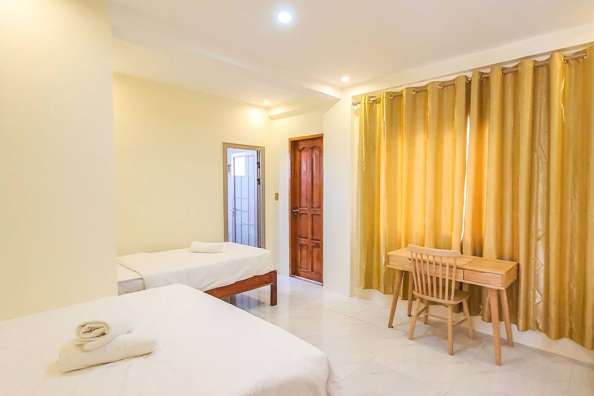 Una habitación de hotel con dos camas, un escritorio de madera y una silla.