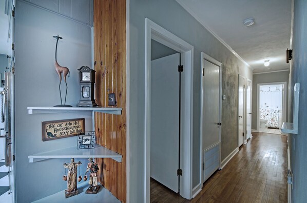 A hallway with wooden paneling, a giraffe figurine, a clock, and a sign.