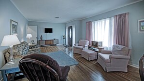 A living room with a sofa, armchairs, a wooden coffee table, and a TV mounted on the wall. - 7 minutes from Providence Farm, MS Blues Trail and The Petrified Forest! (Flora)