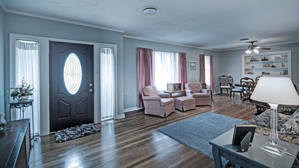 A spacious living room with a dark wooden floor, a large window with curtains, a sofa set, a coffee table, and a ceiling fan. - 7 minutes from Providence Farm, MS Blues Trail and The Petrified Forest! (Flora)