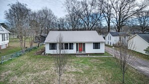 A single-story house with a red front door, a small front yard, and a metal fence. - 7 minutes from Providence Farm, MS Blues Trail and The Petrified Forest! (Flora)