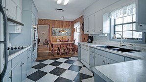 A kitchen with a checkered floor, wooden panel walls, and a dining area with a table and chairs. - 7 minutes from Providence Farm, MS Blues Trail and The Petrified Forest! (Flora)