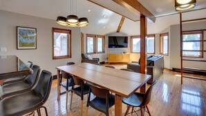 A spacious living area with a wooden dining table, multiple chairs, a sofa, and a television. - Bright Downtown Telluride Condo - Steps to Lift! (Telluride)