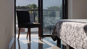 Ein Zimmer mit Bett, Stuhl und Bergblick durch ein großes Fenster.