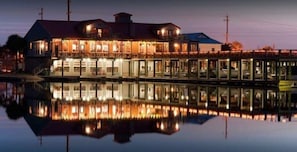 A waterfront hotel with a reflective pool in front, featuring a large building with multiple windows and balconies.