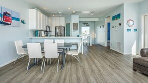 Une cuisine moderne avec des meubles blancs, un îlot central et un coin repas avec des chaises blanches.