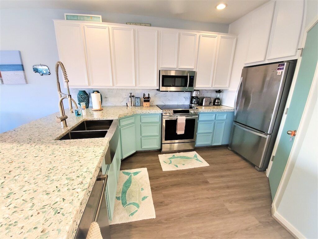 A kitchen with white cabinets, a stainless steel refrigerator, a microwave, and a stove.