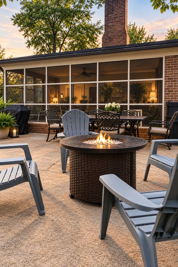 An outdoor patio with a fire pit, wicker chairs, and a dining table.