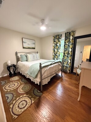 A bedroom with a bed, a nightstand, a chair, a desk, a window with curtains, and a ceiling fan. - Centrally located, 4 bedroom home in beautiful Madison Park (Charlotte)