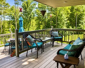 A wooden deck with wicker furniture, a table, and chairs.