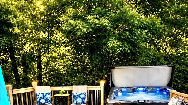 Una terraza de madera con un jacuzzi, mobiliario exterior y una planta en maceta.