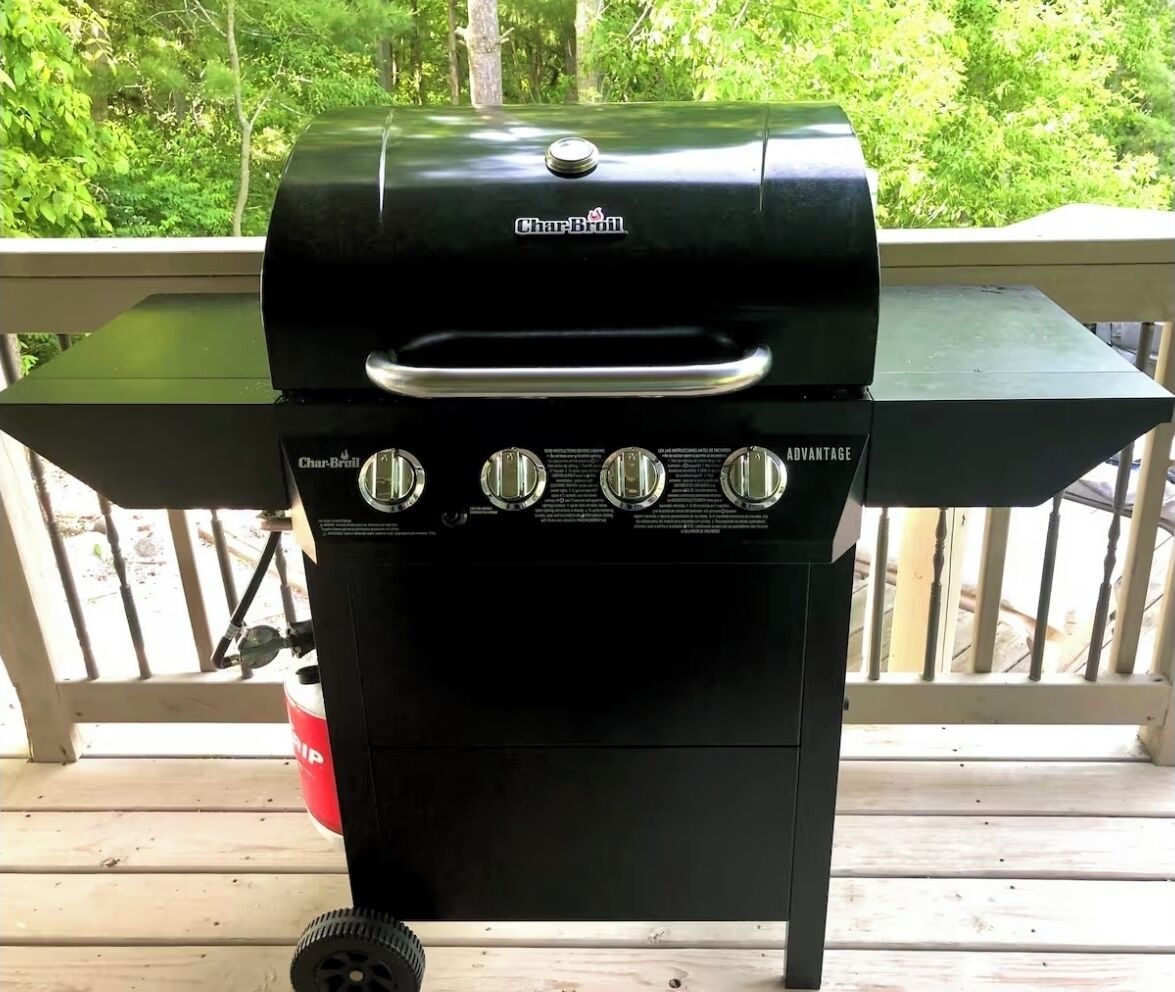 Una parrilla de gas Char-Broil con cuatro perillas de control, una repisa lateral y un tanque de gas.
