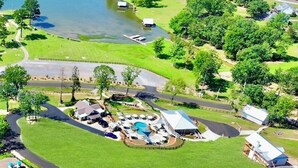 An aerial view of a lakeside property with a swimming pool, guest cabins, and a well-maintained lawn. - LAKEFRONT Mini-Resort Sleeps 32! Pool, hot tub, kayaks, fire pits, & more! (Cedar Bluff)