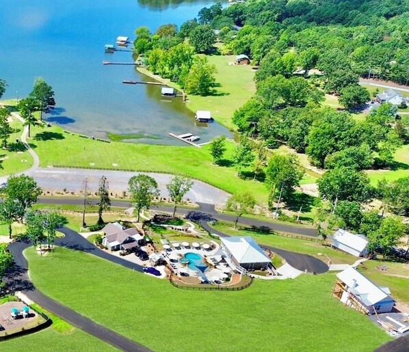 An aerial view of a lakeside property with a swimming pool, guest cabins, and a well-maintained lawn. - LAKEFRONT Mini-Resort Sleeps 32! Pool, hot tub, kayaks, fire pits, & more! (Cedar Bluff)