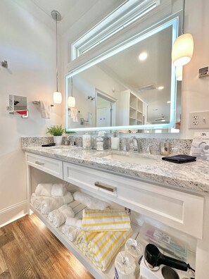 A modern bathroom with a large mirror, granite countertop, and built-in shelves for towels and toiletries. - LAKEFRONT Mini-Resort Sleeps 32! Pool, hot tub, kayaks, fire pits, & more! (Cedar Bluff)
