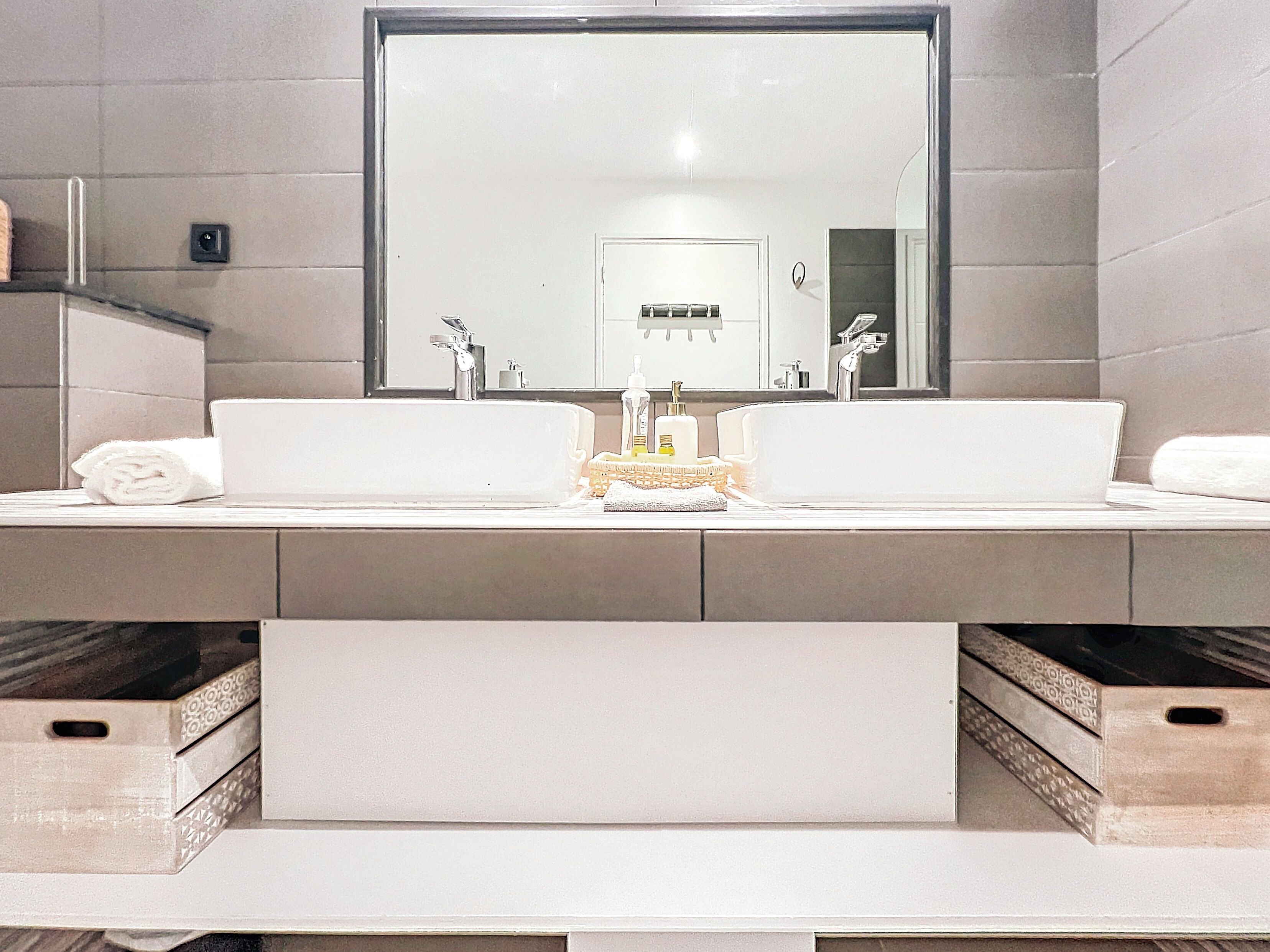 Une salle de bain moderne avec deux lavabos, un grand miroir et un porte-serviettes.