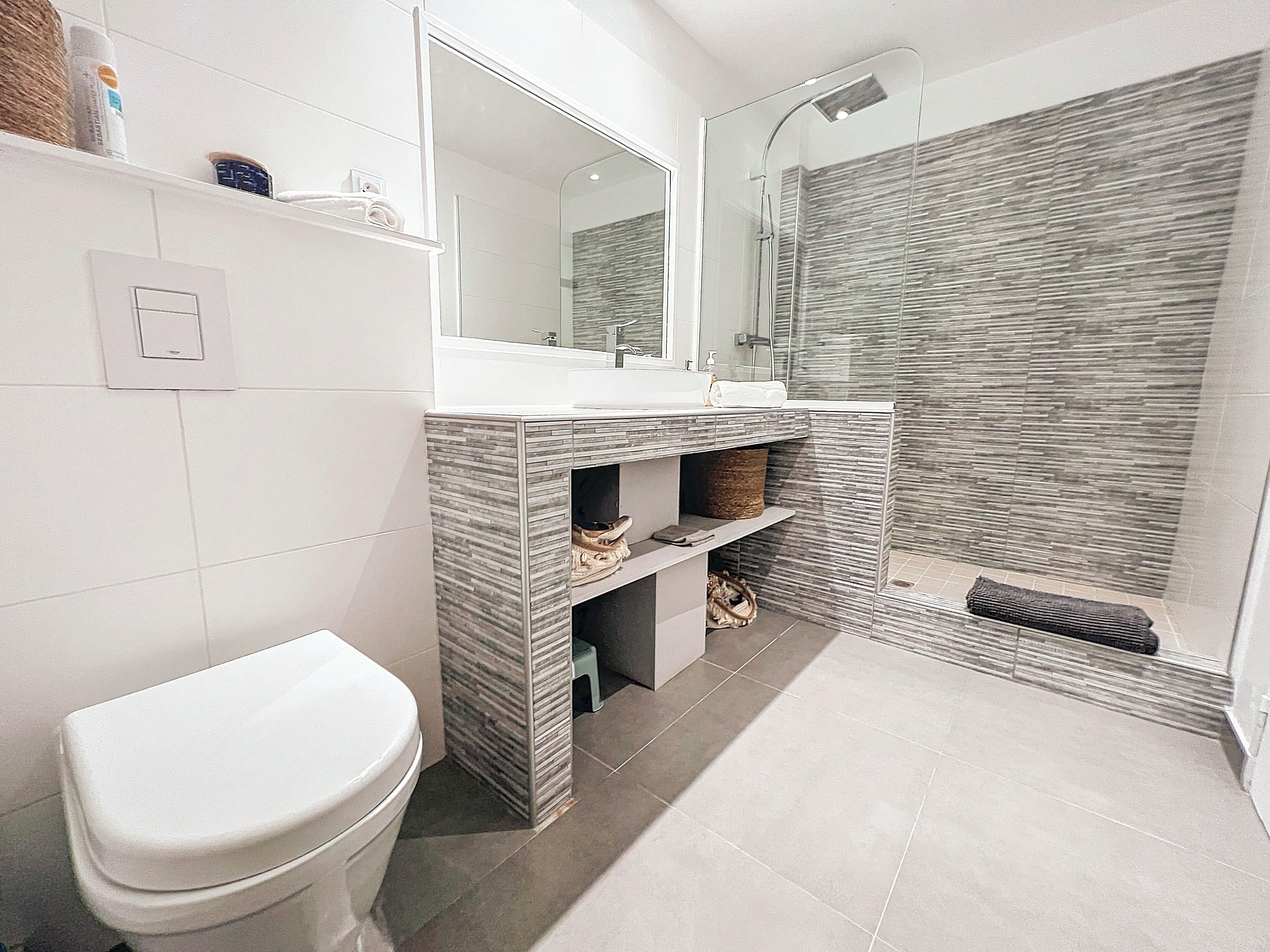Een moderne badkamer met toilet, wastafel en douche.