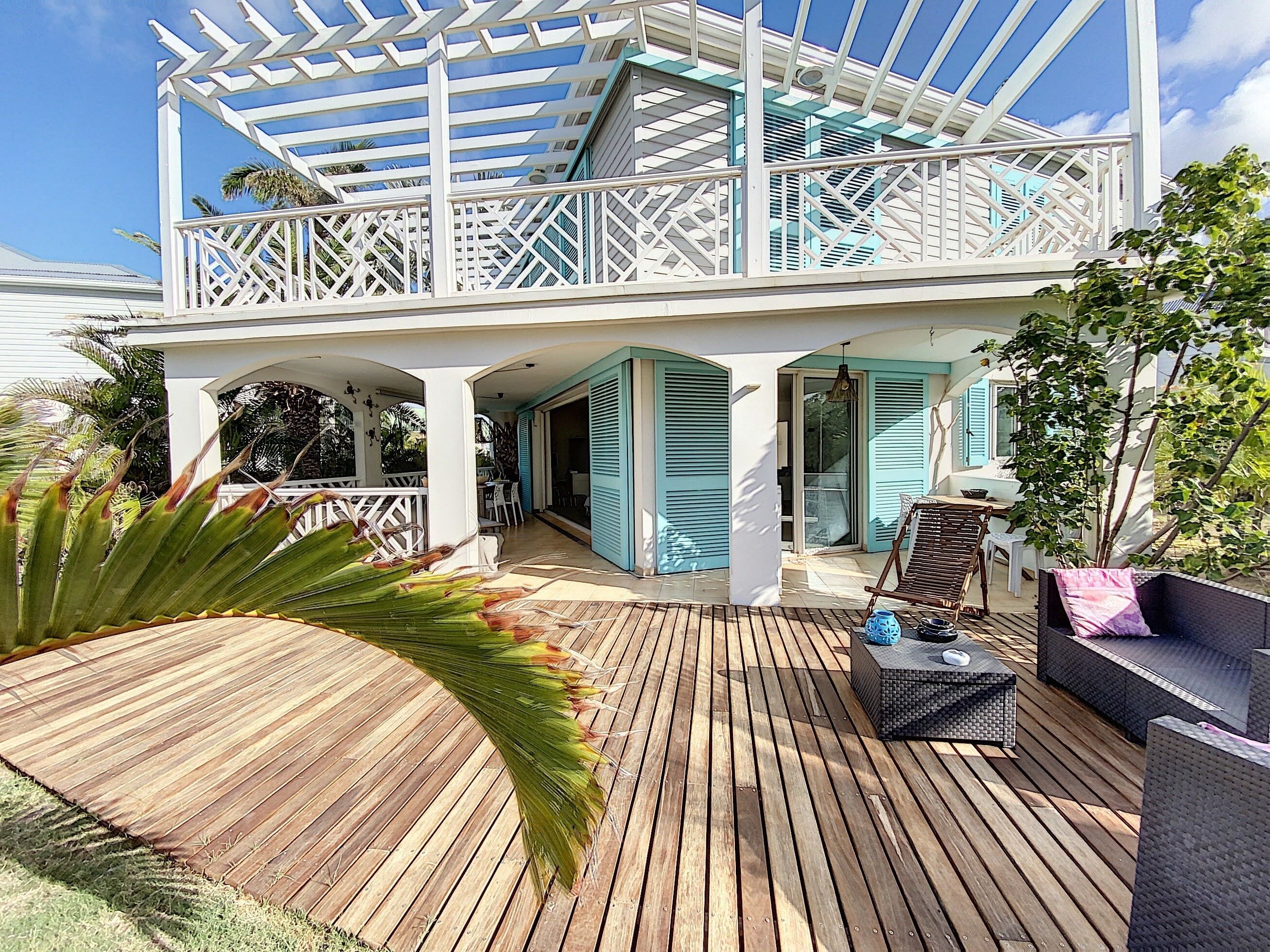 A two-story house with a wooden deck, a covered patio, and a balcony.