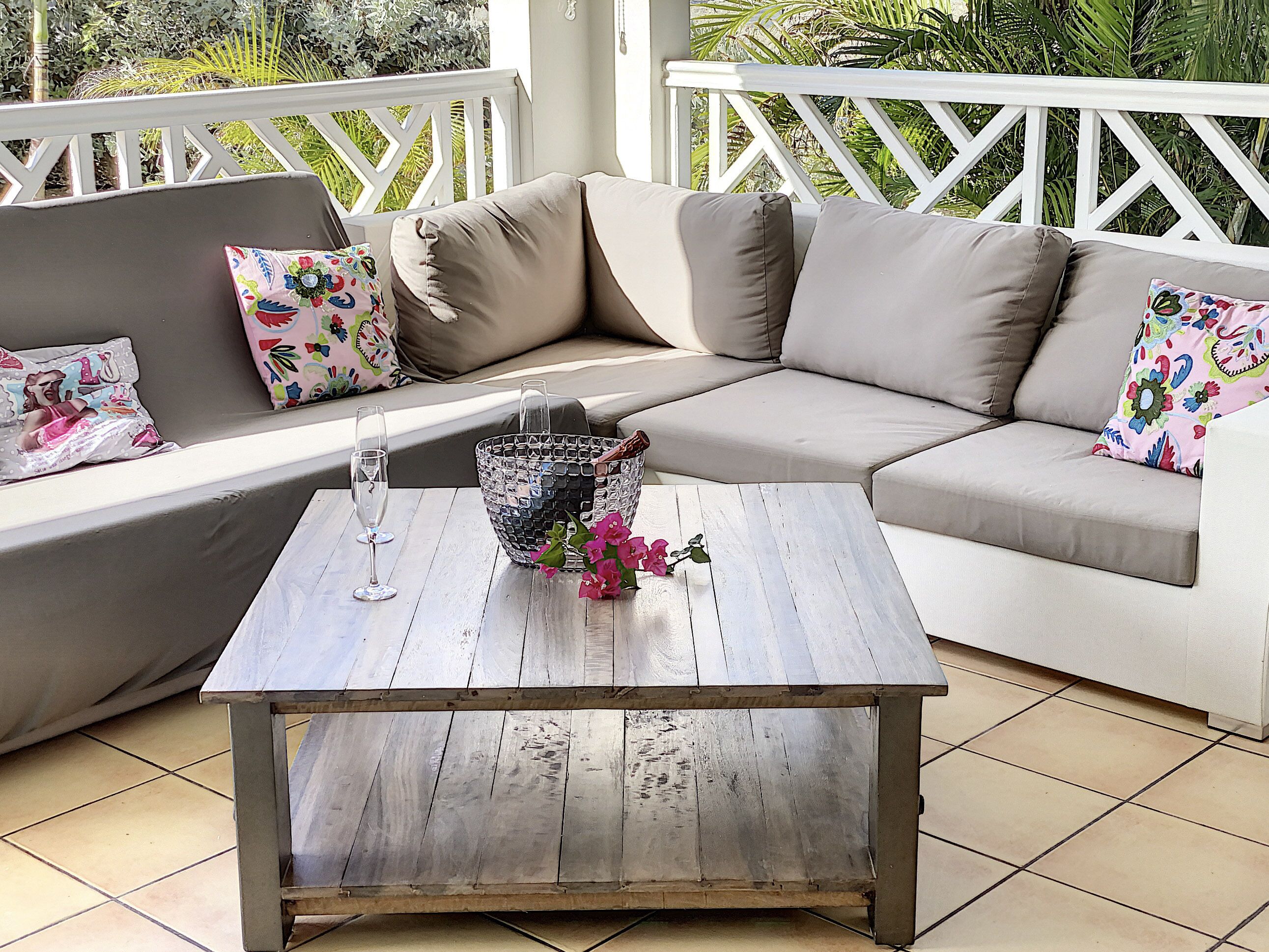 A cozy outdoor seating area with a wooden coffee table, cushioned sofas, and colorful pillows.