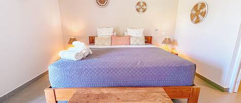 A bedroom with a bed, pillows, a bedside table, and a wall-mounted light fixture.