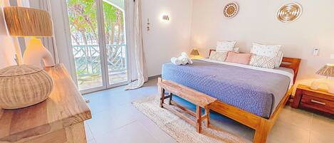 A bedroom with a bed, bedside tables, a bench, and a view through a glass door.