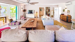 A modern living room with a large sofa, a wooden coffee table, and colorful chairs. - Princess Anaelle · Beachfront, Lage Pool, Privacy, Orient Bay, Deluxe 2 BDR (SAINT MARTIN)