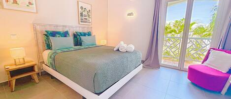 A bedroom with a bed, a nightstand, a chair, and a balcony with a view.