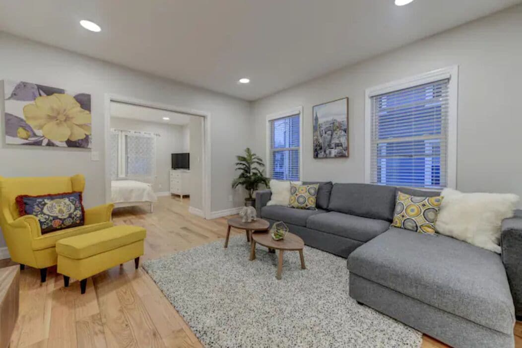 A modern living room with a grey sofa, yellow armchair, and a small coffee table.