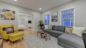 A modern living room with a grey sofa, yellow armchair, and a small coffee table.