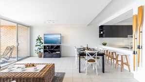 Una cocina moderna con comedor, televisión y vista al mar.