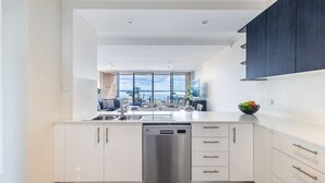 Una cocina moderna con lavavajillas, armarios blancos y vista al mar.