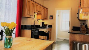 A kitchen with wooden cabinets, a black countertop, a sink, and a stove. There is a vase with yellow flowers on the table.