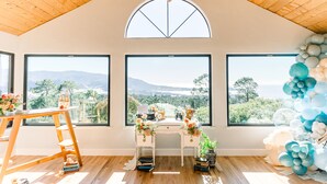 A room with large windows, a wooden ceiling, and a desk with decorative items. - PRIVATE Hilltop Home: Stunning Carmel Views, Hot Tub, 3 Balconies, Espresso (Carmel-By-The-Sea)