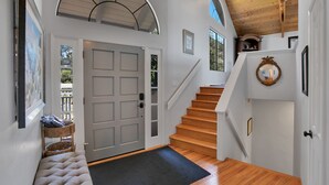 A staircase leading to a second floor with a wooden finish, a white door with a glass panel, and a black doormat. - PRIVATE Hilltop Home: Stunning Carmel Views, Hot Tub, 3 Balconies, Espresso (Carmel-By-The-Sea)