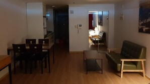 Un espacio habitable compacto con zona de comedor, sofá y una mesita.