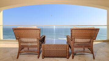 A balcony with wicker furniture overlooking the sea.