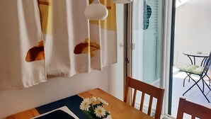 A dining area with a table, chairs, and a window with curtains. - Apartments Trstenica-One Bedroom Apartment with Balcony and Sea View (Orebic)