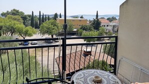 A balcony with a view of a courtyard, a tiled roof, and a table with a decorative centerpiece. - Apartments Trstenica-One Bedroom Apartment with Balcony and Sea View (Orebic)