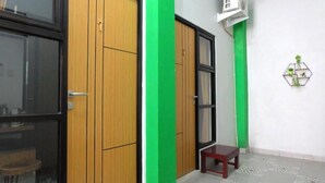 A room with a wooden wardrobe, a small table, and a green accent wall. - Hotel Kili Suci by Simply Homy (Yogyakarta)