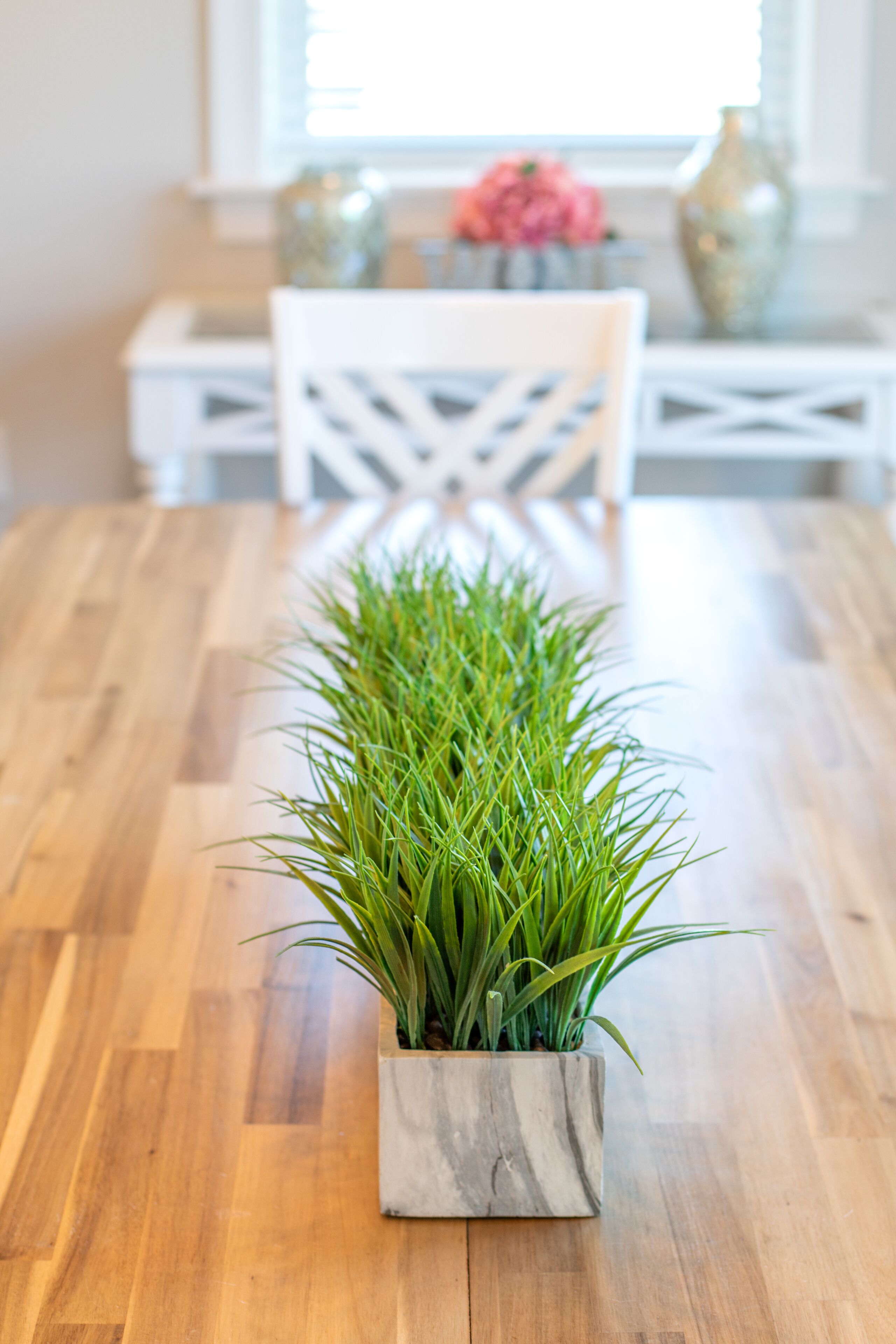 Una mesa de comedor de madera con una planta en maceta en el centro.