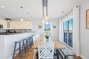 Cocina moderna con armarios blancos, una isla de madera y taburetes de bar.
