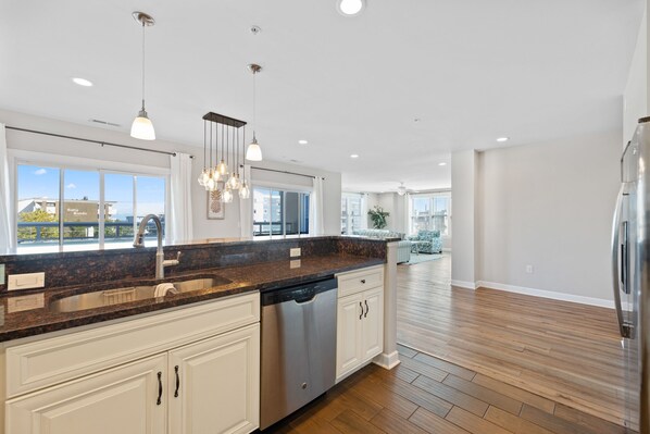 A modern kitchen with granite countertops, white cabinetry, and a dishwasher.