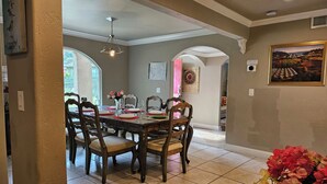 Un coin repas avec une grande table, des chaises et un vase de fleurs.