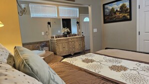 Une chambre à coucher avec un lit, une commode, une coiffeuse et un tableau accroché au mur.
