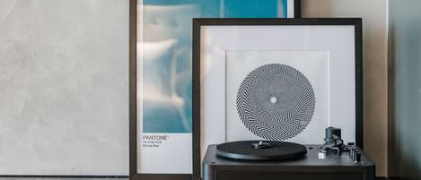 A framed artwork, a turntable, and a tablet on a marble surface.