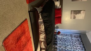A room with a bed, a red and beige wall, and a zebra-patterned rug. - A cozy little place with 2 bedrooms all to yourself (Hartford)